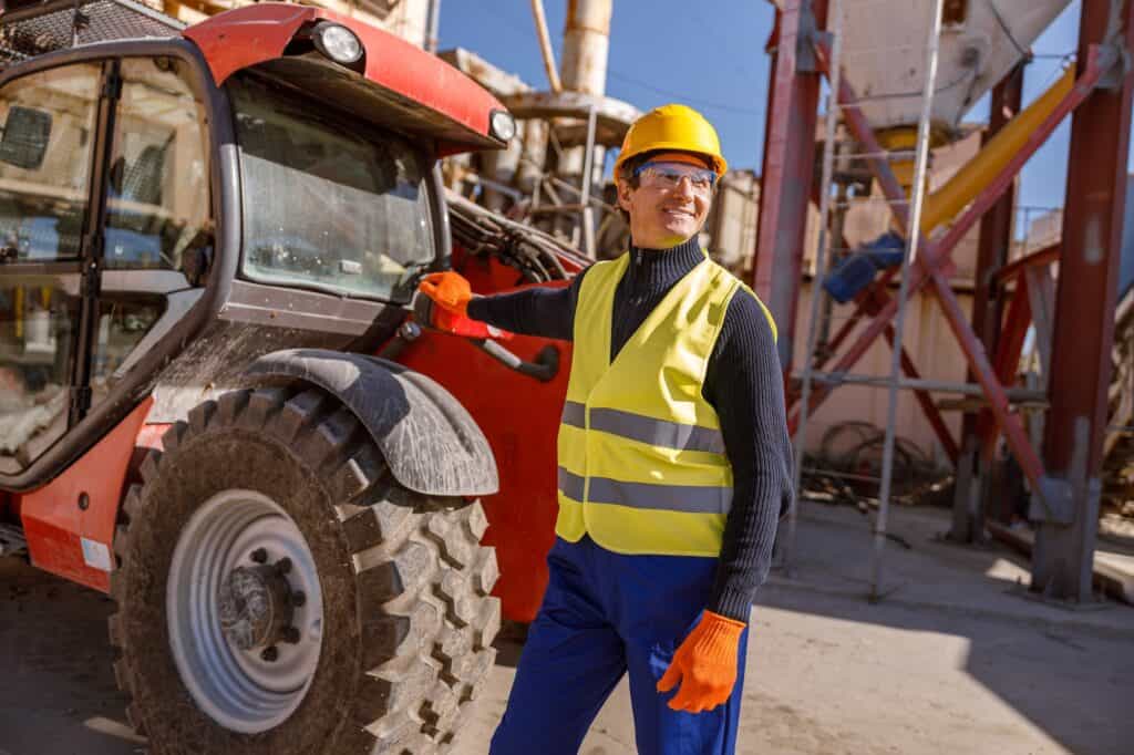 Mann som står atmed en traktor på en fabrikk.